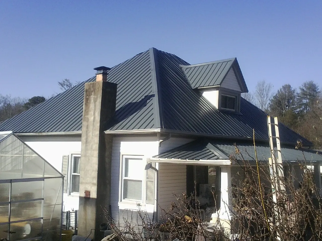 Dark blue standing seam metal roof on a white farmhouse with dormer — Slate & Tile Roof Repair by Roofing Brothers in San Ysidro